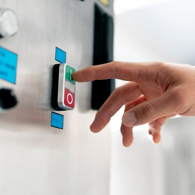Bouton marche arrêt industriel : contrôle de machine Main pressant le bouton marche vert I sur un panneau de commande industriel avec bouton arrêt rouge O.