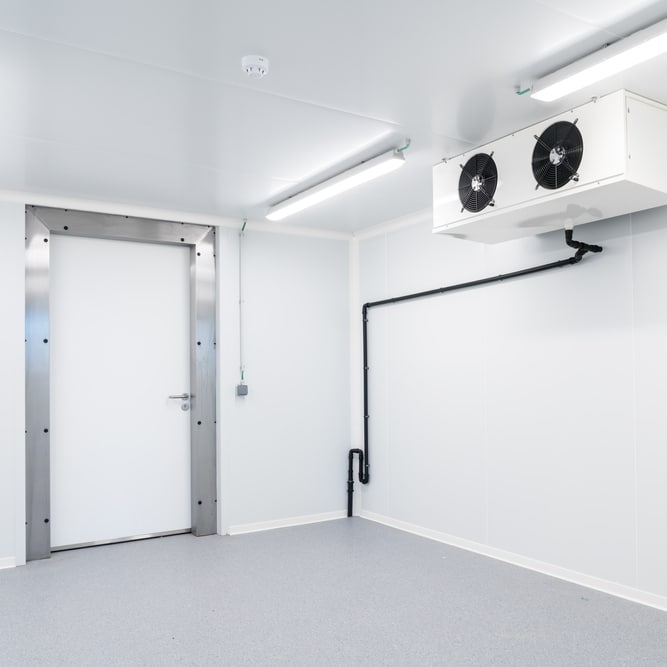 Chambre froide professionnelle pour stockage réfrigéré Chambre froide vide avec porte isolée, unité de refroidissement à deux ventilateurs et murs blancs stériles.